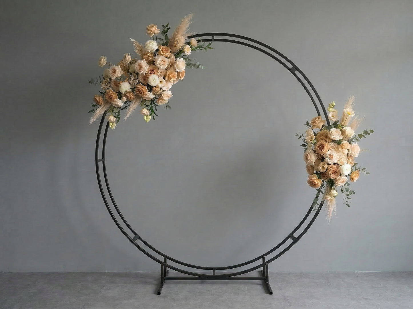 Double circular metal arch with floral decorations against a gray background
