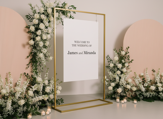 Decorative wedding setup with floral arrangements and a welcome sign in a gold frame.